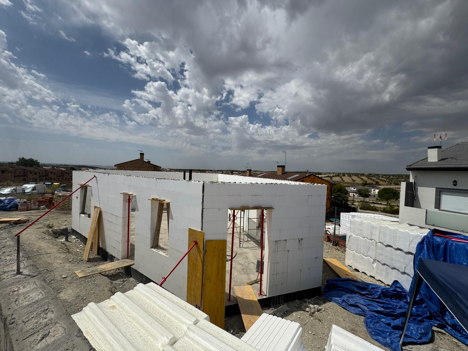 Vivienda en construcción con muros levantados y materiales de obra