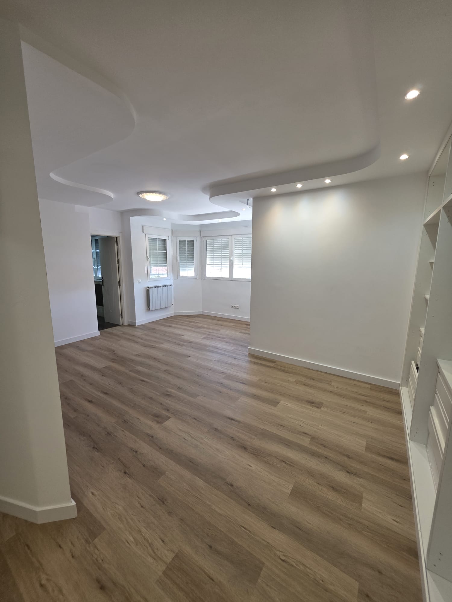 Salón renovado con suelo de madera y techo con iluminación integrada